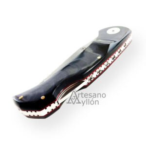 Navaja Muela Navalia 10M-DX cerrada, con mango ergonómico de micarta negra pulida, separadores rojos y forros decorados, sobre fondo blanco.