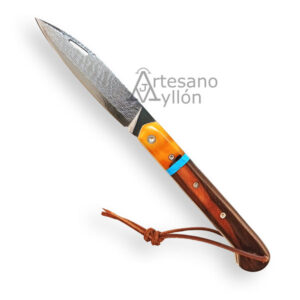 Navaja Miguel Nieto ART5 abierta, mostrando una hoja grabada a mano con patrón ondulado y un mango de ébano Macassar con virola de hueso de camello y anillo azul de malaquita. Lleva un cordón de cuero atado al extremo del mango.