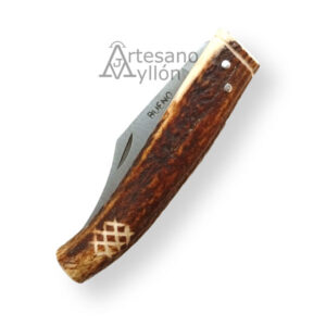 Navaja Bueno curva de 9 cm cerrada, con mango de asta de ciervo natural, mostrando la textura rugosa, los remaches metálicos y la hoja parcialmente visible.
