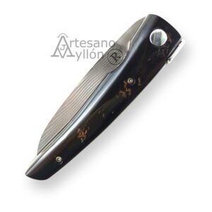 Navaja artesana RGC Amaru RG2 cerrada, mostrando mango de cuerno de cebú negro con vetas marrón rojizas, tornillería metálica visible y hoja parcialmente alojada en el interior, diseño compacto de 95 mm cerrada, fondo blanco.
