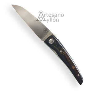 Navaja artesana RGC Amaru RG2 abierta, con hoja satinada de acero N-690 de 73 mm, punta drop point y acabado liso, mango oscuro de cuerno de cebú pulido con vetas naturales marrón oscuro y negro, tornillería visible y sistema liner lock, fondo blanco neutro.