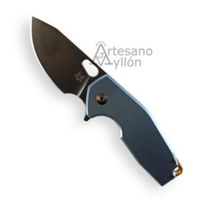 Características Principales: Hoja: – Material: Acero Böhler M390 – Longitud: 60 mm – Grosor: 4,0 mm – Tipo: Filo liso con recubrimiento Black PVD Mango: – Material: Titanio anodizado azul – Longitud: 88 mm (aprox.) – Anclaje: Estructura integral con frame lock – Extras: Espaciador en latón con acabado stone washed, tornillos y clip en titanio con recubrimiento Black PVD Dimensiones: – Longitud total: 148 mm – Longitud cerrada: 88 mm – Longitud de la hoja: 60 mm – Peso: No especificado Mecanismo de Bloqueo: – Tipo de bloqueo: Frame Lock (bloqueo integrado en el mango)