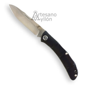 Navaja Salamandra Tek 841523 abierta sobre fondo blanco, con hoja satinada de acero laminado núcleo M390 y laterales 420, punta ligeramente caída y vaciado plano. Mango negro de fibra vegetal Flax reforzada con resina epoxi, con tres remaches visibles, emblema circular metálico incrustado y orificio para rabiza en la parte trasera.