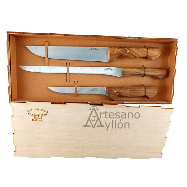 Juego de cuchillos para cortar jamón Campins con tres cuchillos de acero inoxidable y mangos de madera de olivo, presentados en una caja de madera con interior acolchado sobre fondo claro.
