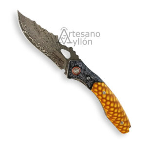 Navaja Tramuntana N197J abierta con hoja de acero damasco VG10 de 67 capas con patrón ondulado visible, apertura tipo agujero, mango acrílico JUMA en tono ámbar con textura escamada y detalles grabados en la zona metálica.